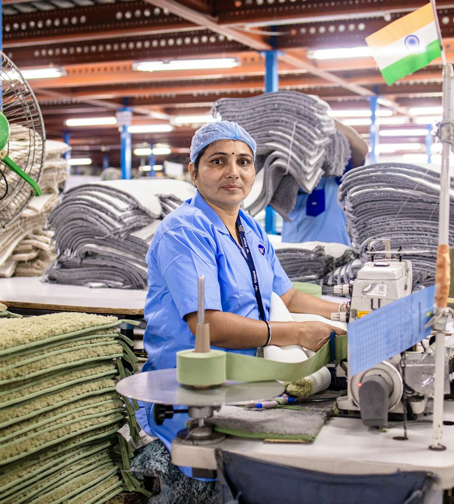 A factory worker in India, smiling at the camera on the shop floor